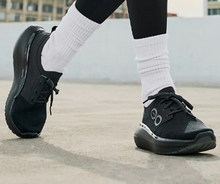 Load image into Gallery viewer, Person wearing black athletic shoes with white socks on a concrete surface.