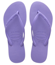 Load image into Gallery viewer, Product photograph of Havaianas flip-flops featuring a pair of vibrant lavender rubber sandals with textured rice pattern soles and visible Havaianas brand logos on the straps and oval heel patch