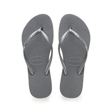 Load image into Gallery viewer, Digital photography of a pair of metallic grey Havaianas flip-flops featuring textured soles and straps with the brand name embossed