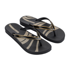 Load image into Gallery viewer, A pair of black Ipanema flip-flops with beige and black wavy stripes on the footbeds and gold trim on the straps, shown on a plain white background.
