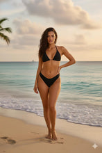 Load image into Gallery viewer, Woman in a black bikini standing on a beach with ocean and sky in the background
