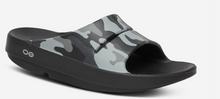 Load image into Gallery viewer, A single slide sandal with a black footbed and sole, featuring a gray and black camouflage pattern on the upper strap, shown against a light gray background.
