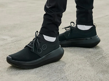 Load image into Gallery viewer, Black athletic shoes worn with black pants on a concrete surface
