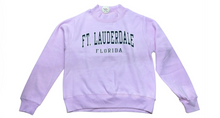 Load image into Gallery viewer, A light purple crewneck sweatshirt with 'FT. LAUDERDALE' and 'FLORIDA' printed in dark green varsity-style lettering on the chest, displayed flat against a white background.
